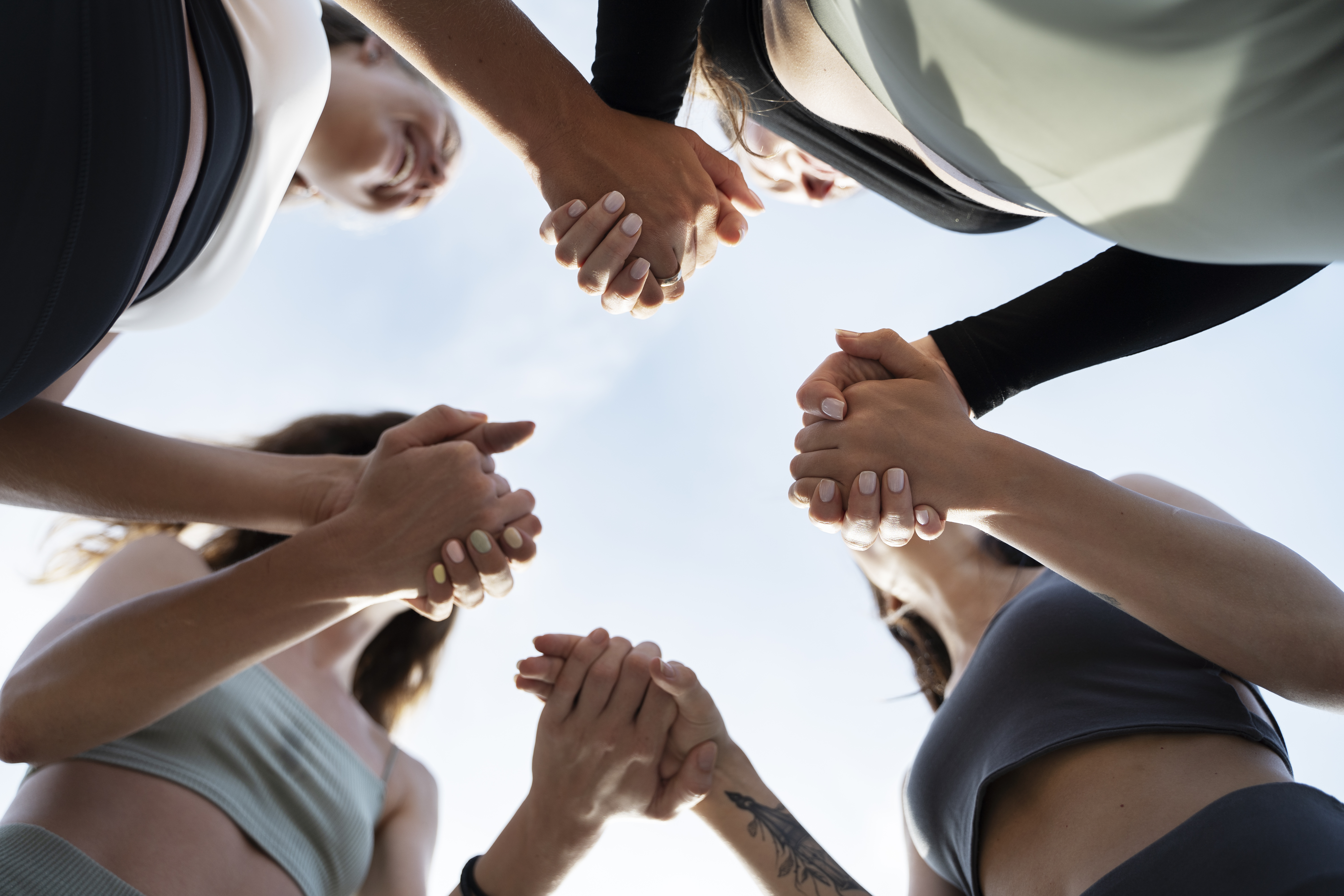 Groupe de participants mains jointes pour symboliser la cohésion du programme collectif